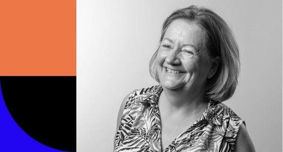 Katie Taylor is shown in a headshot-style photograph. She's shown wearing a sleeveless blouse and smiling towards the corner of the room.