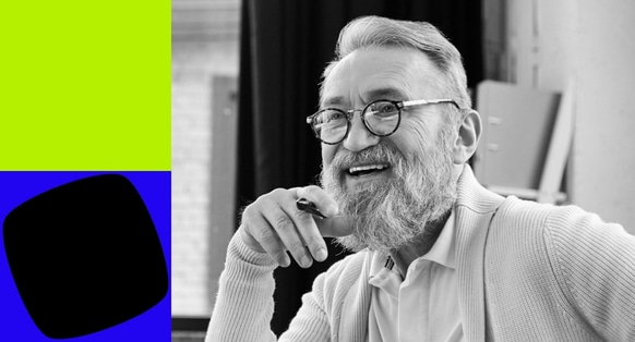 A smiling man with glasses with green and blue shapes