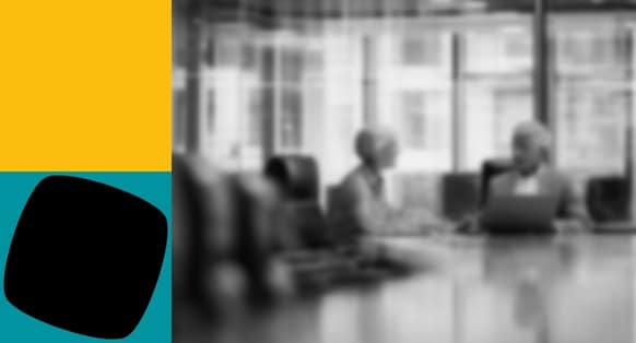 A black and white blurred image of people at a desk with yellow and teal shapes on the left hand side