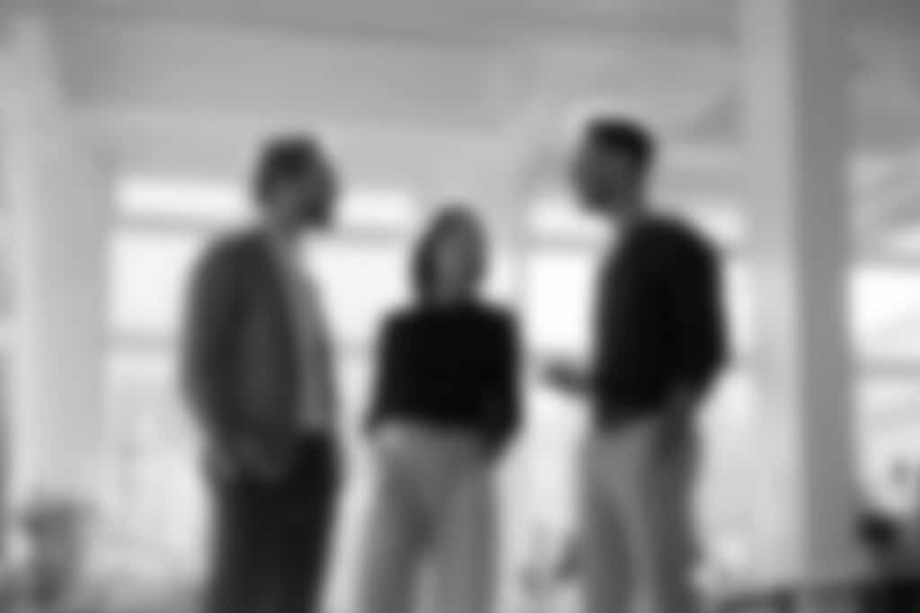 Blurred black-and-white image of professionals in conversation, representing the Agile Business Consortium community