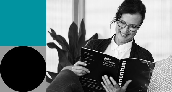 A black and white image of a lady reading a magazine